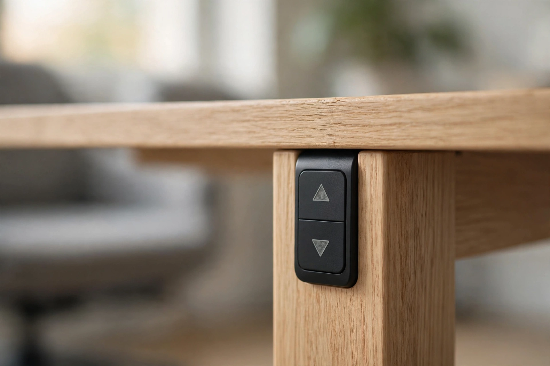 Close-up of a standing desk's height-adjustment control panel with up and down arrow buttons mounted on a wooden desk leg
